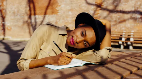 woman sitting on bench writing by hand