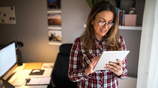 A woman stands and works on a tablet