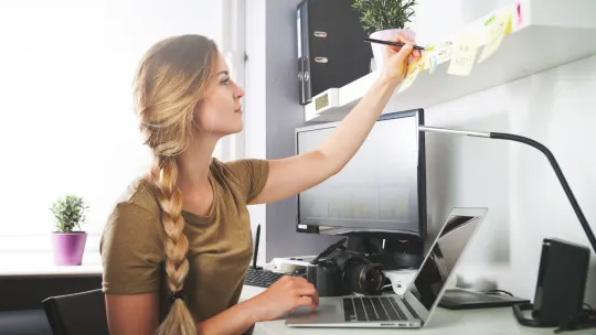 woman sitting at desk writing on Post-It notes