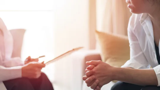 psychiatrist taking notes while in session with a patient