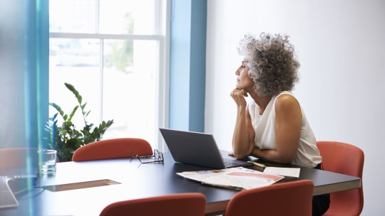 older woman on laptop thinking