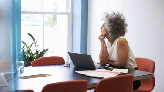 A woman in an office holds a coffee mug