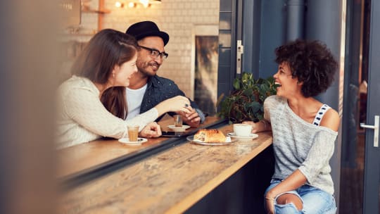 Three friends sit outside at a cafe
