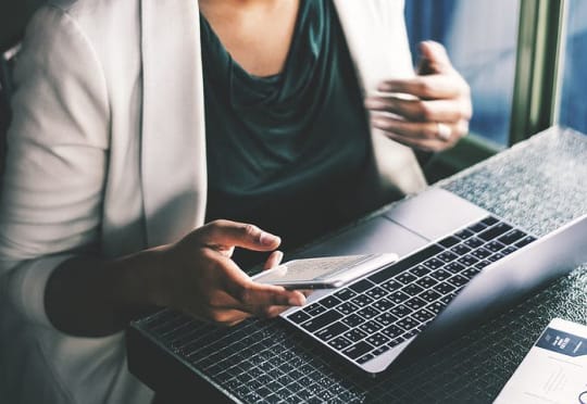 woman in front of computer holding phone