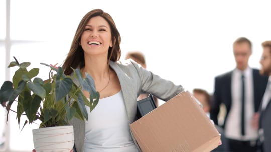 woman carrying a box of her possession out of the office