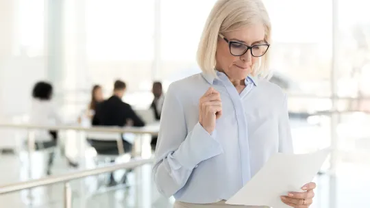 older woman holding a piece of paper at work
