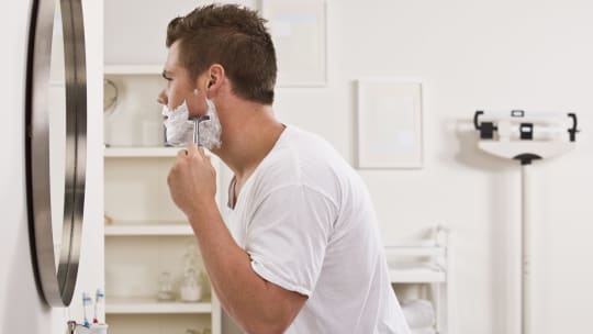 Man shaving in mirror