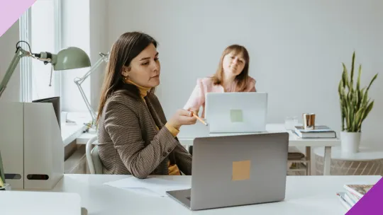 Two women at an office, illustrating that you can lear how to ask for help at work without sounding incompetent