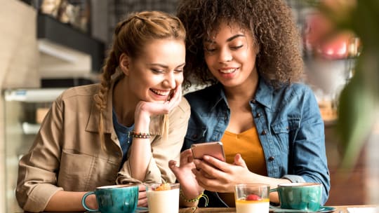 two women laughing at phone