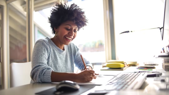woman laughing happily while writing