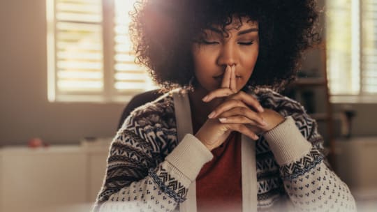 A woman sits at a desk thinking
