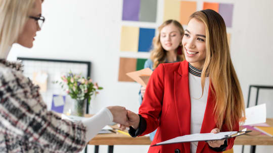 attractive businesswoman holding red jacket and looking away in office