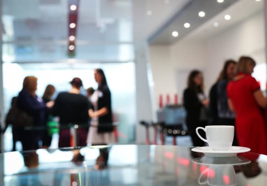 Coffee and saucer foreground, people mingling in background