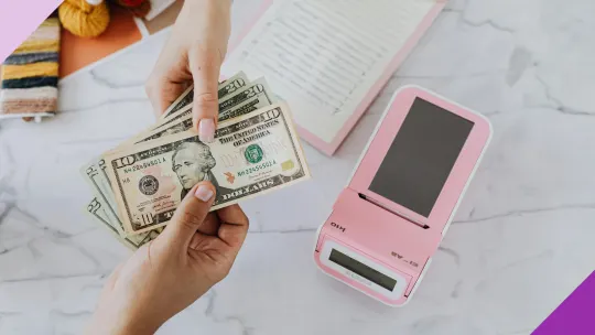Two hands in what looks like a store passing money to each other, illustrating the importance of learning how to spend less money