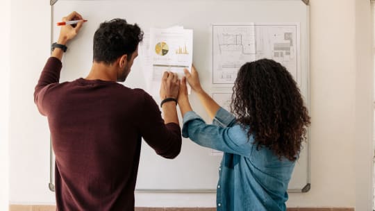 Business partners discussing work on a whiteboard in office