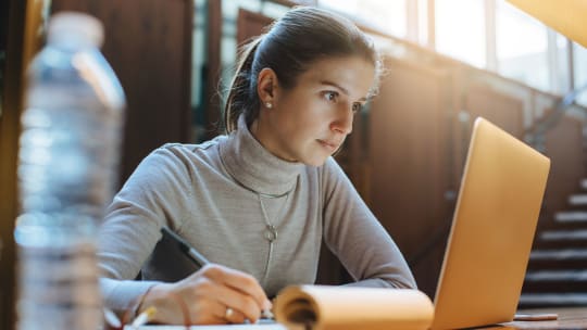 woman on laptop taking notes