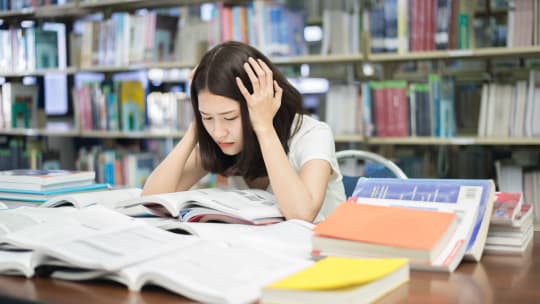 frustrated college student surrounded by textbooks