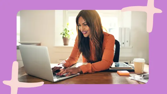 a woman smiling and working on a laptop