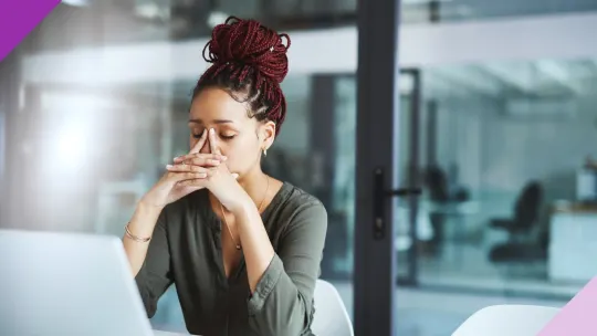 person sitting at their desk in an office with the head in their hands