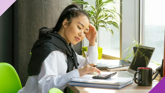 A professional in her 30s using a calculator