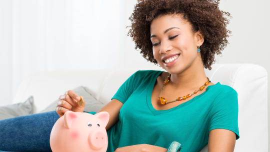 woman putting money in piggy bank