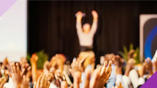 A woman on a stage facing a crowd, illustrating that many celebrities overcame fear of public speaking to pursue their passion 