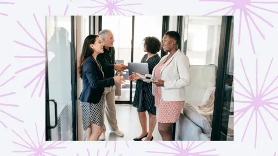 four people shaking hands in an office