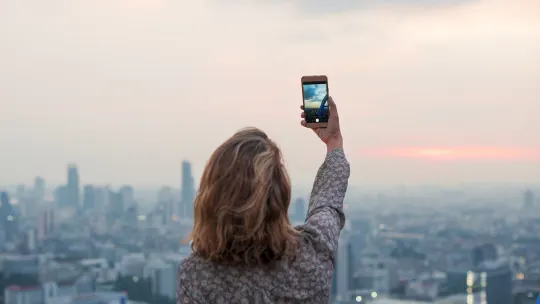 Woman outside taking a picture with her phone