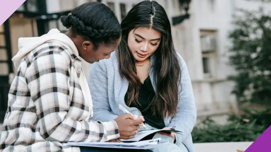 Two young women studying, illustrating the employer student loan repayment benefits