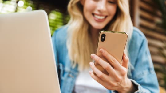 Woman on computer and looking at phone