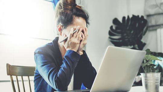woman in front of her laptop with her face in her hands