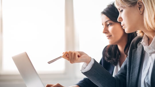 two women pointing at a computer