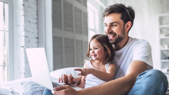 dad working with daughter in his lap