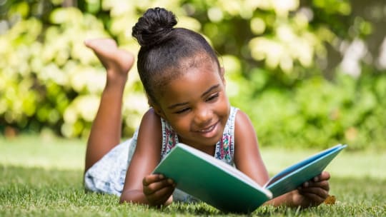 little girl reading outside