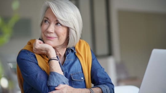 senior woman looking pensive at home with laptop