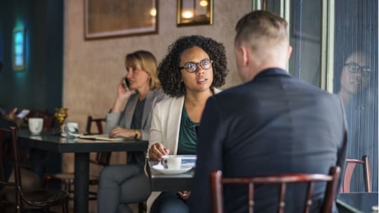 Unhappy woman facing a man at a coffee shop table