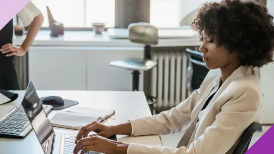 A woman working at an office to illustrate how using AI for work can make you more productive. 