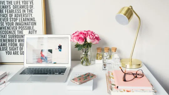 A laptop on a desk with a blog post on the screen.