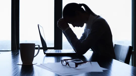 woman at her desk with her head in her hands
