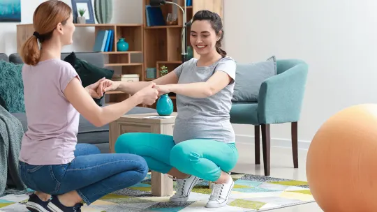 Doula and pregnant woman doing exercises at home