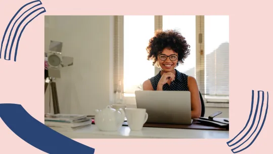 a woman smiling behind a laptop.