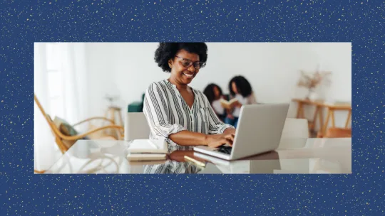 Woman smiling while typing on laptop.
