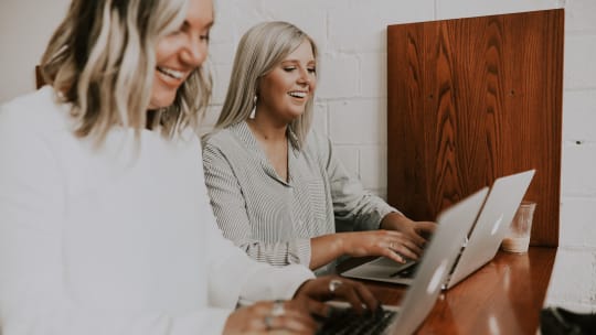 Two women sitting in front of laptops