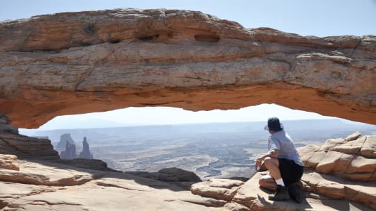 park ranger sitting on rocks under a branch