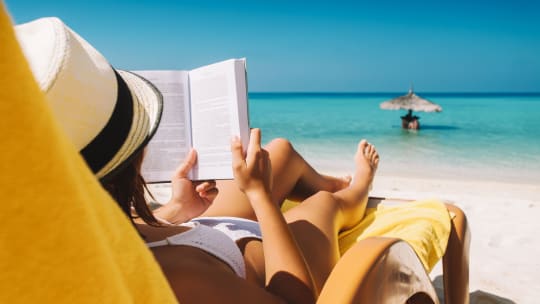 woman laying on the beach reading