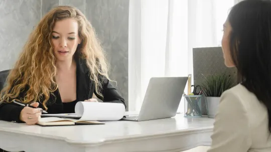 woman meeting with career counselor, who is taking notes.