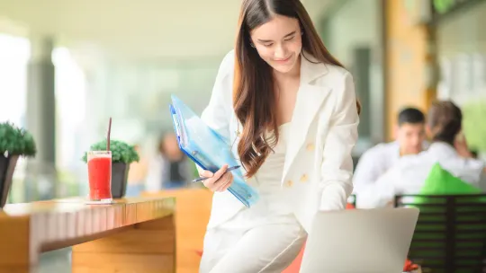 A woman smiling down at a computer.