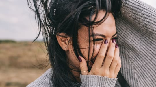 woman laughing with hand to her face