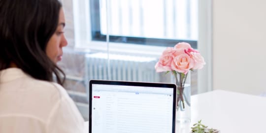 Woman sending email on her phone while sitting at a desk