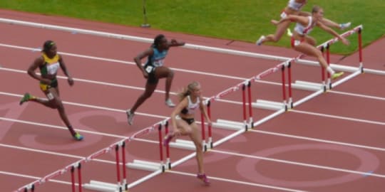 Women jumping over hurdles